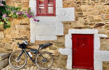 Bike leaning against stone wall with red door and window