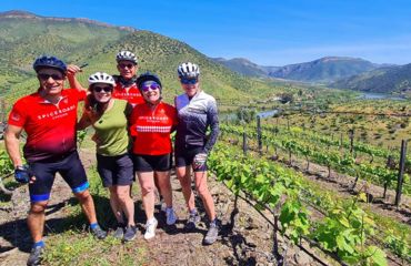 Group of cyclists off the bike posting for photo near vineyards