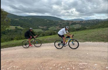 Two cyclists riding up rural road