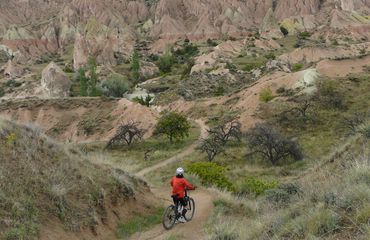 Cyclist in middle of trail looking at red mountains