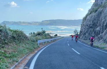 Cyclists road riding around mountain with sea in background