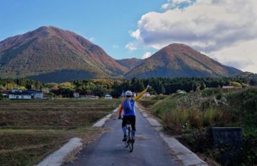Cyclist riding on path towards several mountains