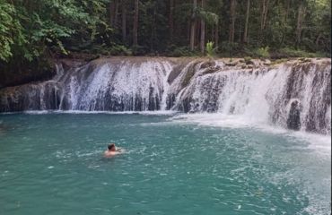 Small waterfall and swimmer in the waters below