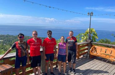 A group of people in cycle jerseys on deck overlooking ocean