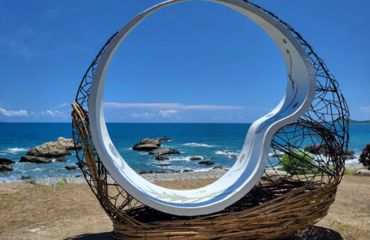Circular see-through sculpture with sea in background