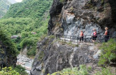 People hiking on path by side of mountain