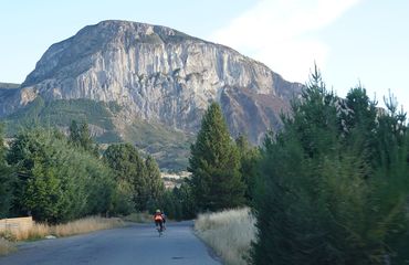 Cyclist on road with rising mountain