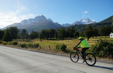 Cyclist on road with snow-capped mountains