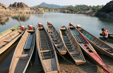 Small wooden boats moored on still water with arid mountains in background
