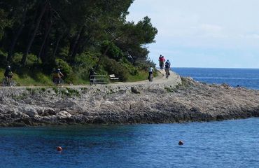 Cyclists riding around path by the sea