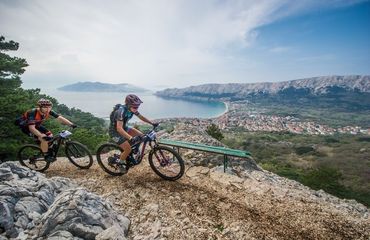 Mountain bikers on rocky path overlooking town and ocean