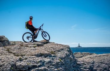 Mountain biker on rocky outcrop looking out to sea