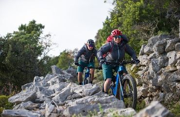 Couple on mountain bikes riding through rocky trail