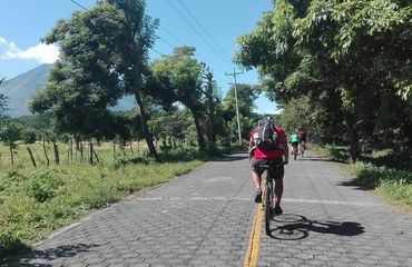 Cyclists on paved road next to countryside