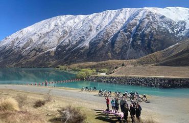 Cyclists in front of lake and snow covered mountain