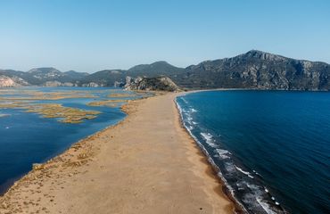 Spit of sand with water on each side and mountains in background