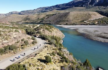 Cyclists on road by side of lake with mountain