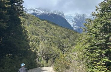 Cyclist on gravel road towards snow capped mountains
