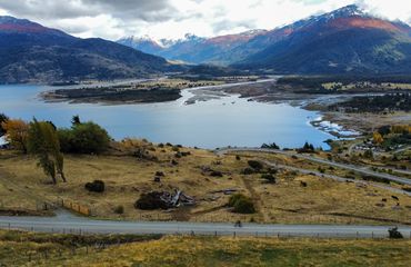 Road next to lakes with red mountain views beyond