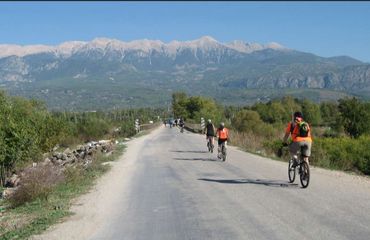 Cycling down dusty road with mountain in background