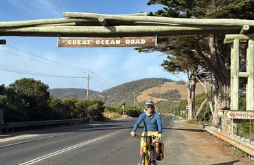 Cyclist riding under Great Ocean Road sign