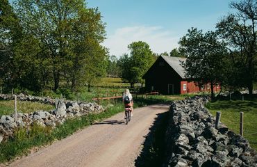 Cyclist riding down countryside lane to red building