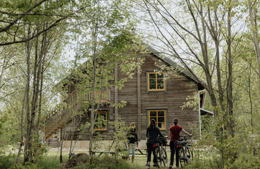 Building in woods with cyclists outside