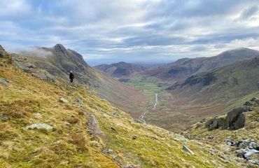 Person standing on mountain looking down valley