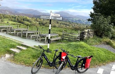 Two bikes on stands by a UK fingerpost sign in countryside