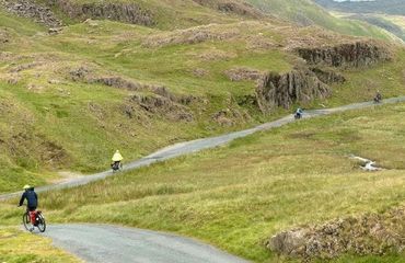 Cyclists on road in green mountain scenery