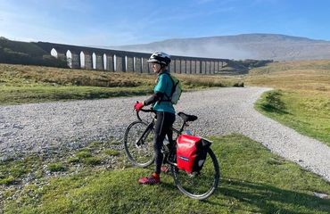 Cyclist looking at viaduct with mountain behind