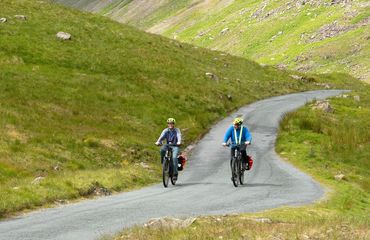 Two cyclists on green hilly road