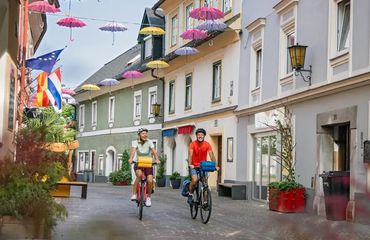 Cyclists riding down street with umbrellas suspended