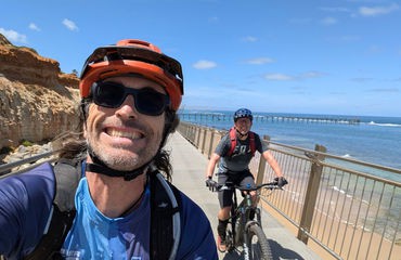 Two cyclists riding by the sea