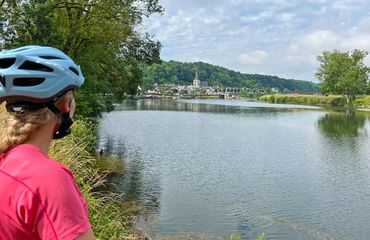Women wearing cycle helmet looking over water at castle and village view