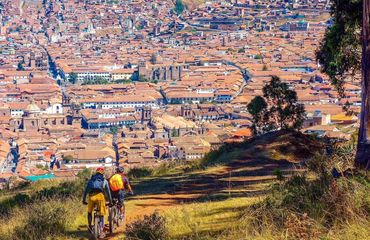 Two cyclists riding high above a city
