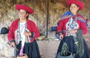 Two Peruvian women in traditional dress dyeing material in pots