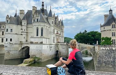 Cyclist, off the bike, sitting opposite a castle