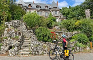 Cyclist standing at foot of stairs with historic building up a hill