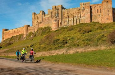 Cyclists riding past castle on hillside