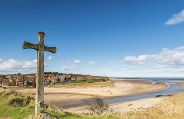 Cross by the side of the sea, with a village in the background
