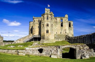 Ancient Castle with blue sky behind and green lawn to the front