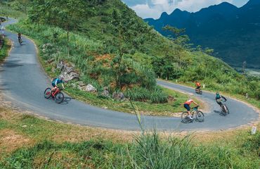 Cyclists riding fast down a curved road