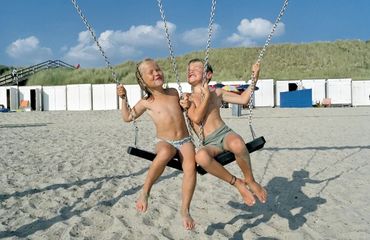 Kids playing on the swings at a beach