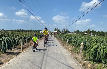 Adult and child cycling on a paved path between fields