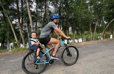 Adult riding bike with small child on seat on back