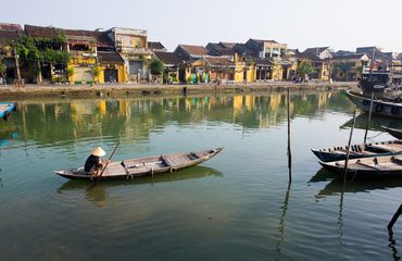 Person in traditional boat rowing down river in Vietnam