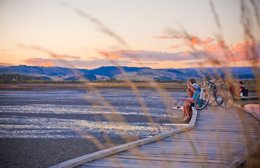 Cyclists sitting on boardwalk at sunset