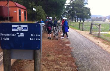 Rail trail sign and group of cyclists gathered by track