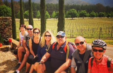 Group of people sitting by vineyard, posing for photo